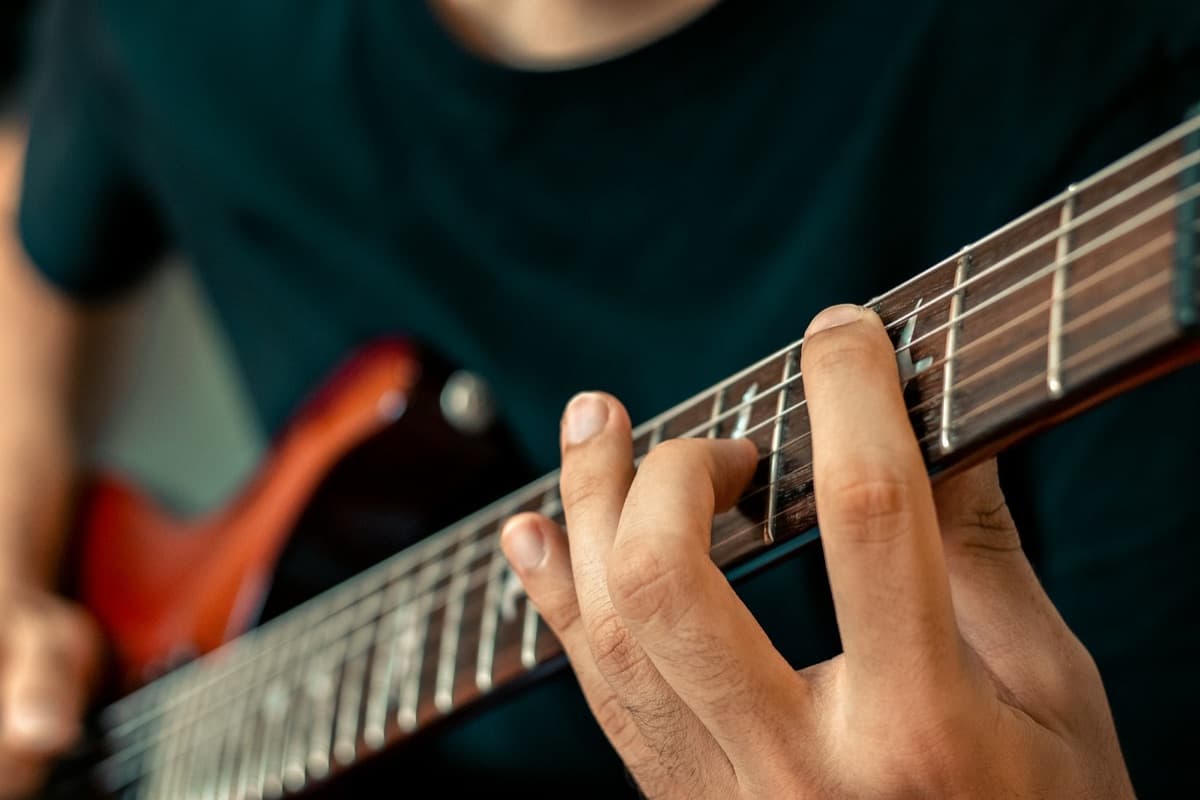 Hand fretting a chord on an electric guitar