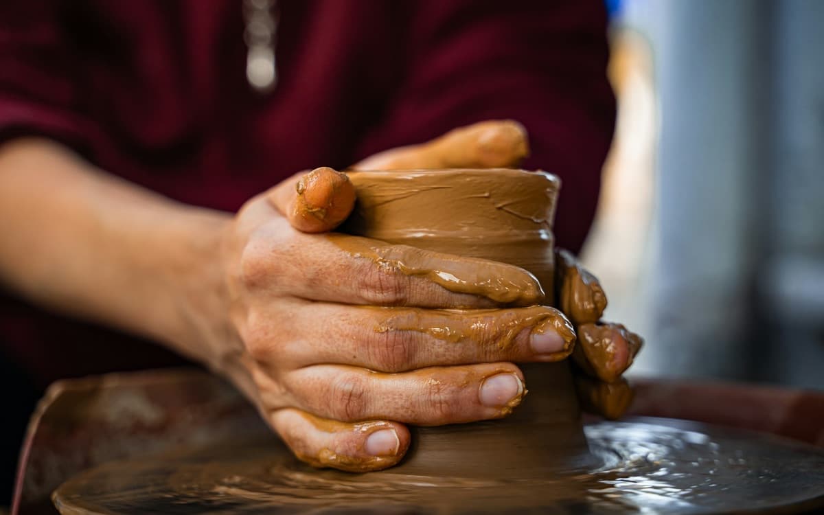 Hands shaping wet clay on a pottery wheel